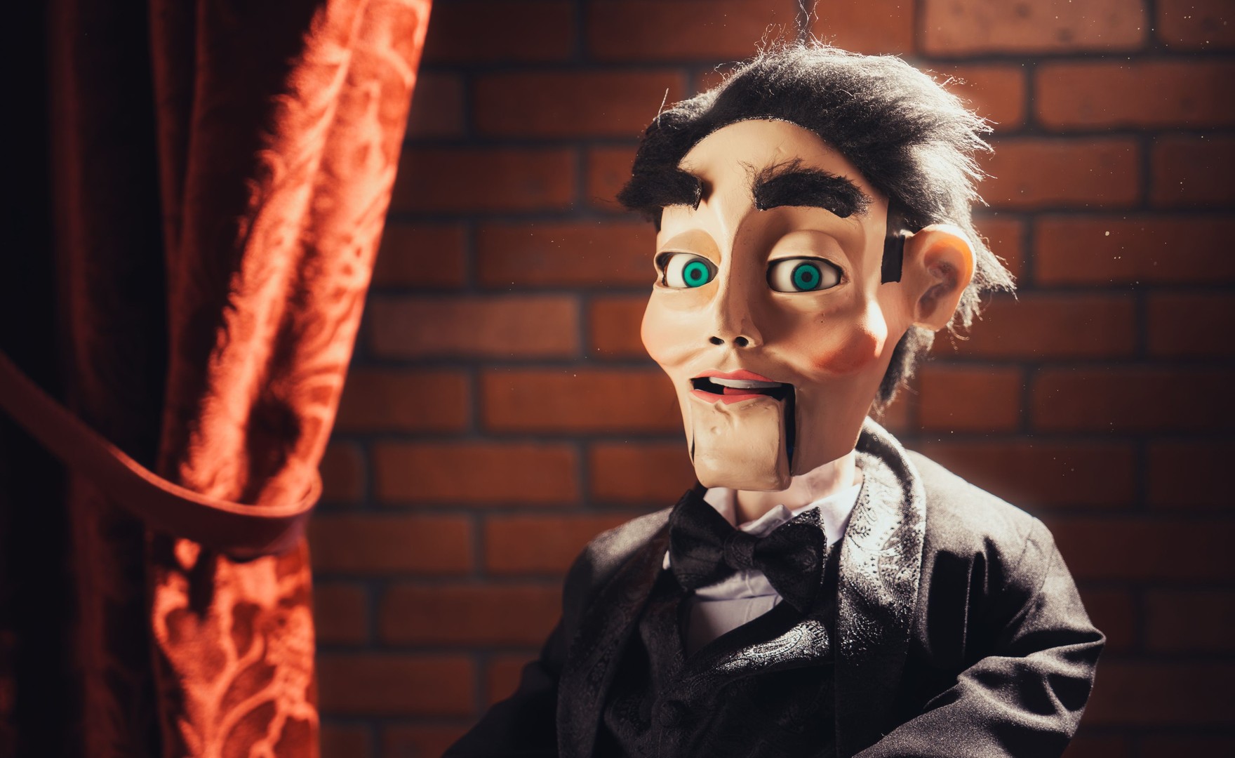 Photo of ventriloquist dummy in front of a brick wall
