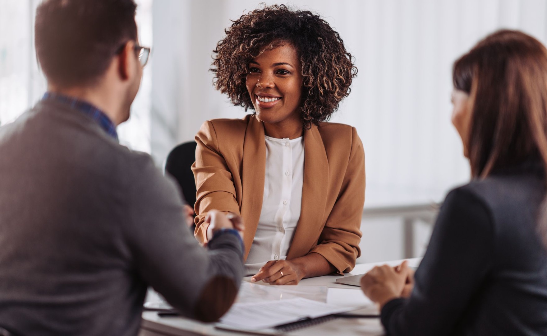 Smiling woman in office smiling and shaking hands with a man