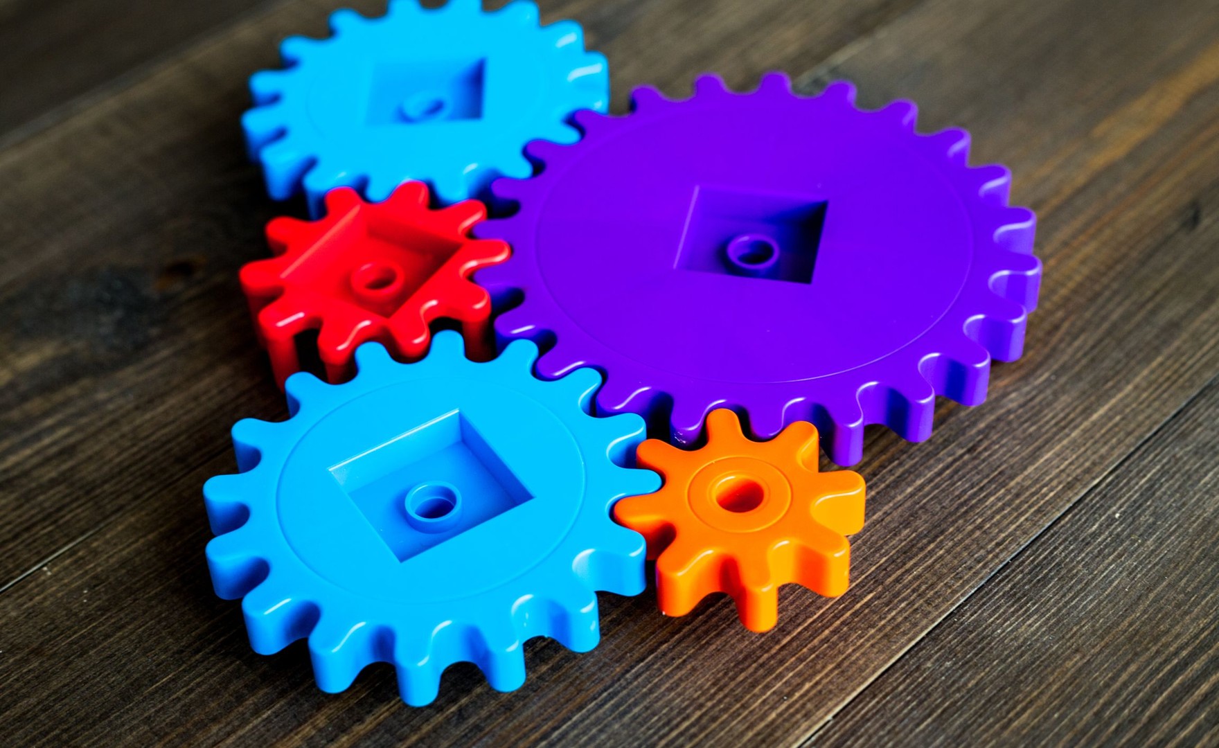 A group of colourful, plastic cogs and gears working together
