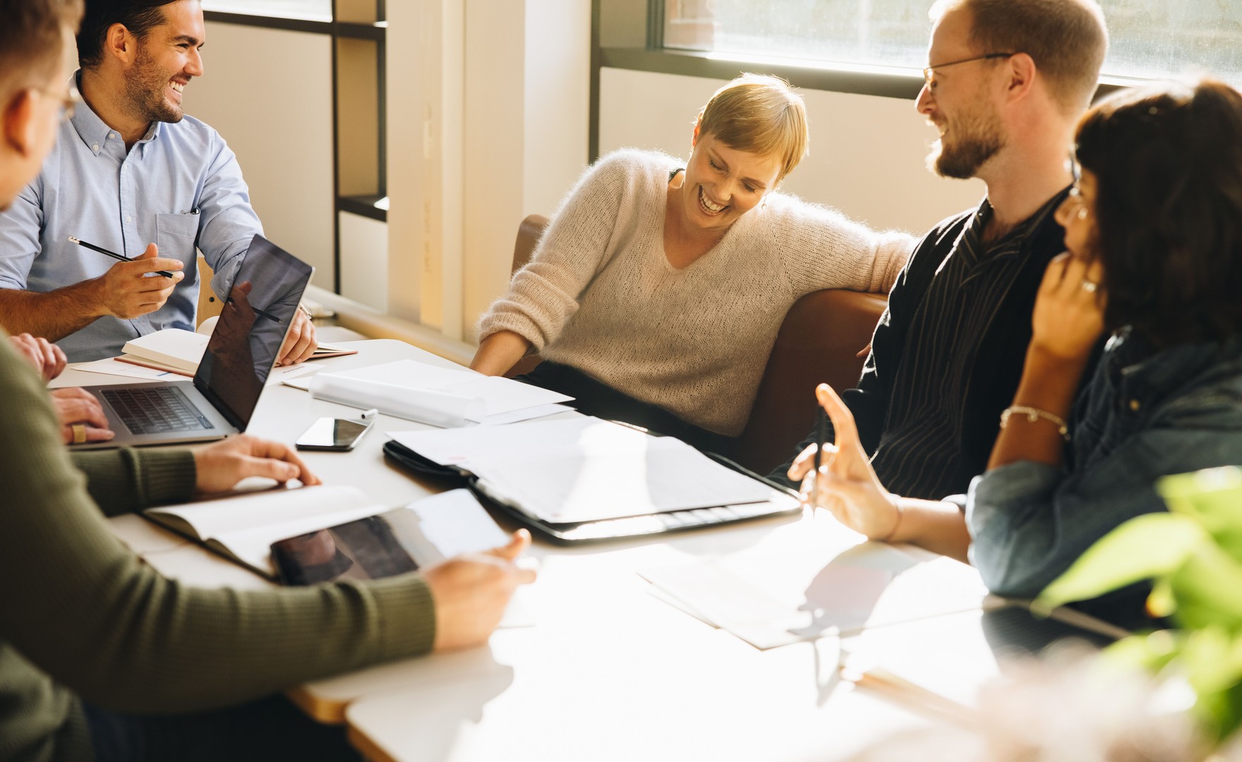 Colleagues sat at a table in an office laughing together